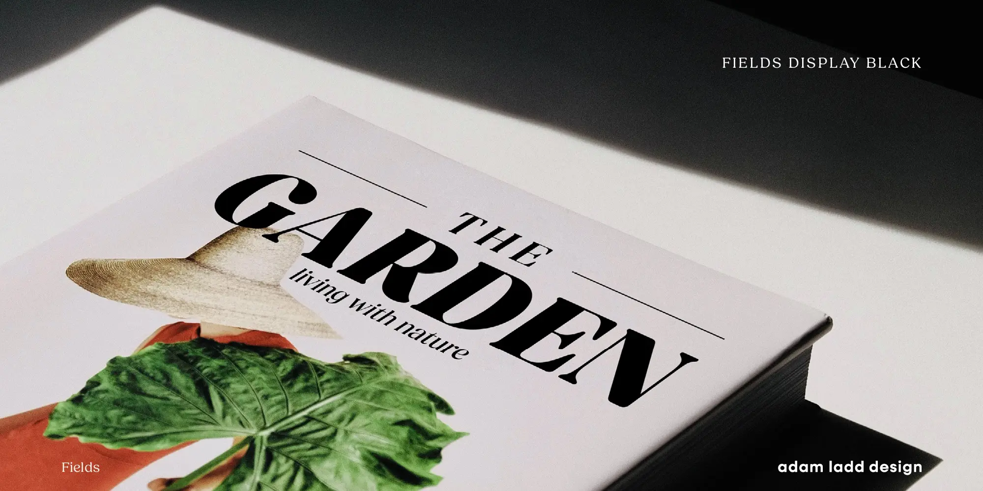 Fields font by Adam Ladd Design — a book cover with the upright serif words “THE GARDEN” and the italic words “living with nature” over an image of a person in a straw hat holding a large green leaf